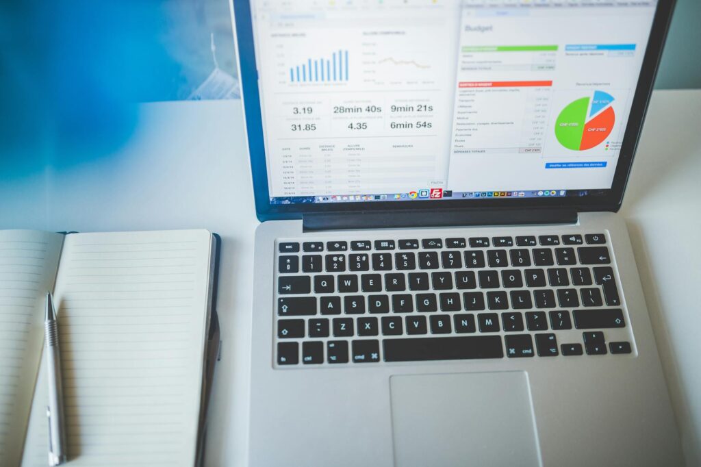 Laptop displaying charts and graphs next to a notebook, ideal for business and tech themes.