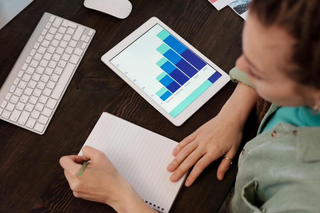 A woman taking notes while analyzing data on a tablet, ideal for business and technology themes.