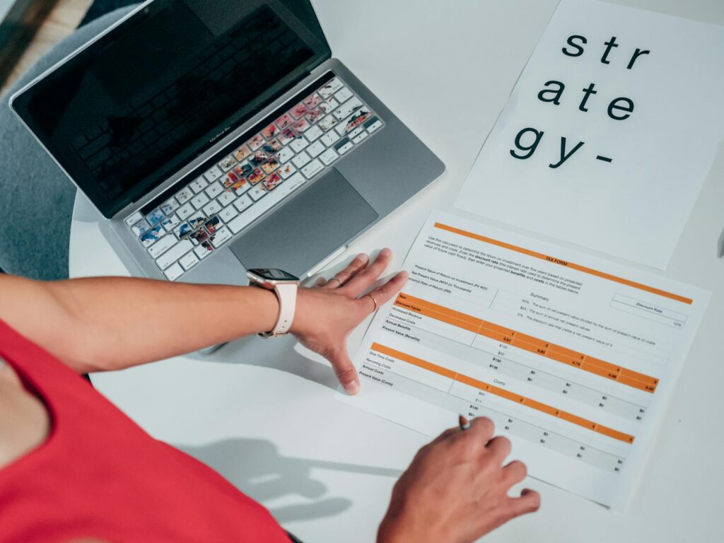Overhead view of hands on business strategy papers with laptop, highlighting modern planning.