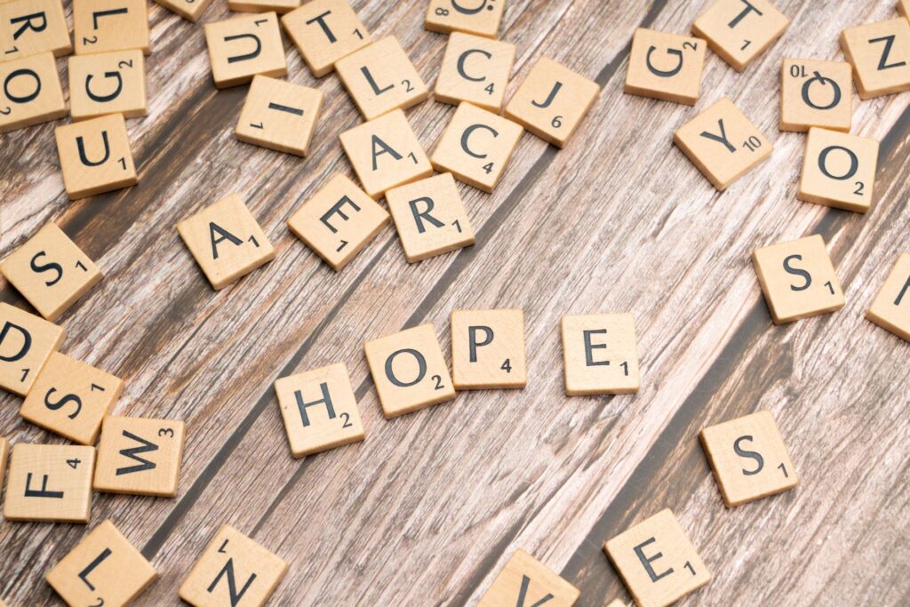 Scrabble tiles spelling 'hope' on a rustic wooden background, symbolizing inspiration.