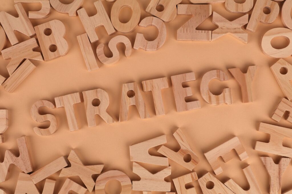 Overhead view of wooden letter blocks spelling 'Strategy' on a soft brown background.