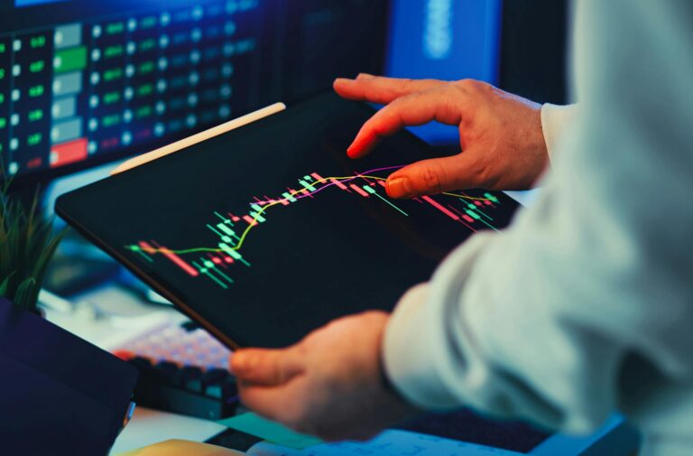 A close-up of a person using a tablet to analyze stock market trends and charts indoors.