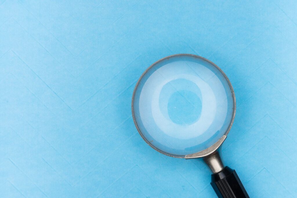 Close-up of a magnifying glass on a blue background, focusing on detail and clarity.
