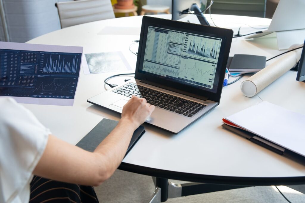 Business person evaluating financial charts on a laptop in a modern office setting.