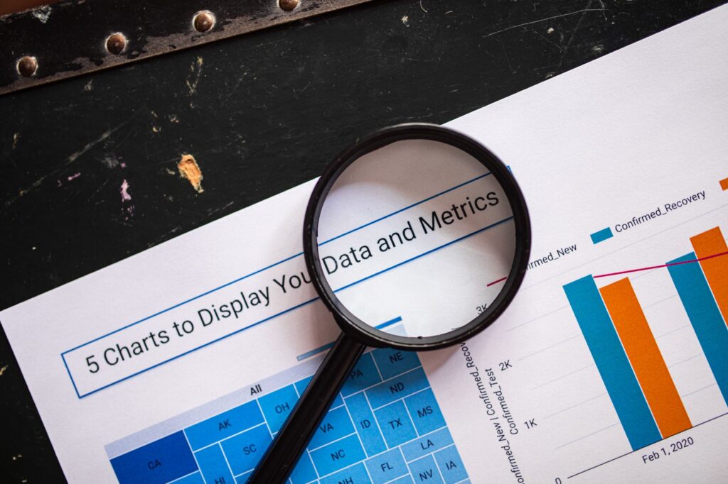 Close-up of a magnifying glass over financial data charts and metrics on printed paper.