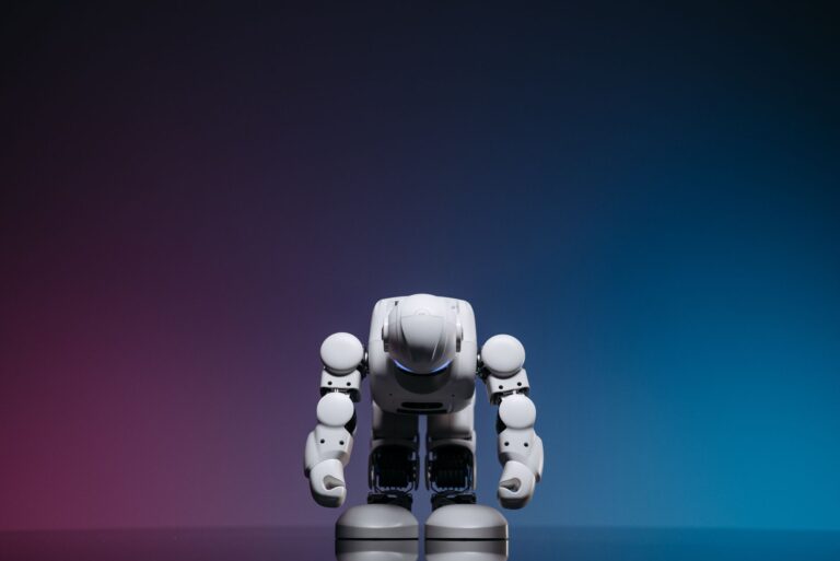 White robot in a bowing pose against a gradient studio background.
