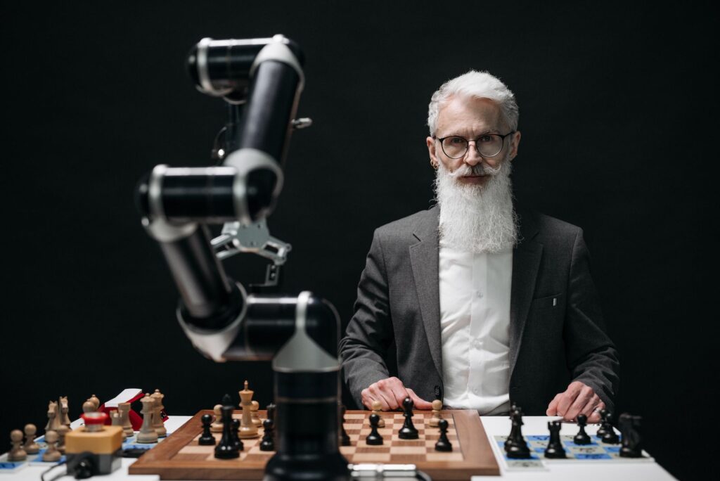 Elderly man in suit competes against a robotic arm in an intense chess game.
