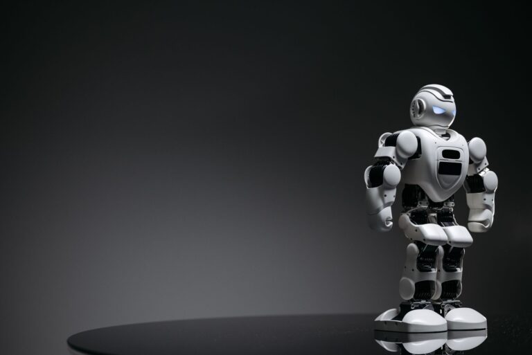 Compact humanoid robot toy standing on a reflective surface, exuding a futuristic vibe.