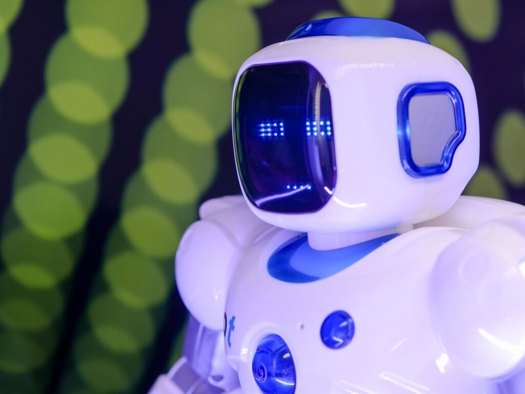 Close-up of a modern humanoid robot with glowing blue features on a green abstract background.
